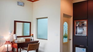 Une chambre d’hôtel avec un bureau en bois, une chaise, un miroir, une fenêtre et une porte donnant sur une salle de bain.