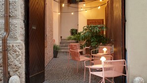 A narrow alleyway with a wooden door, a staircase, and a seating area with wicker chairs and tables. - Goldengel Suite 2, 60sqm, air conditioning, WiFi (Kaltern)