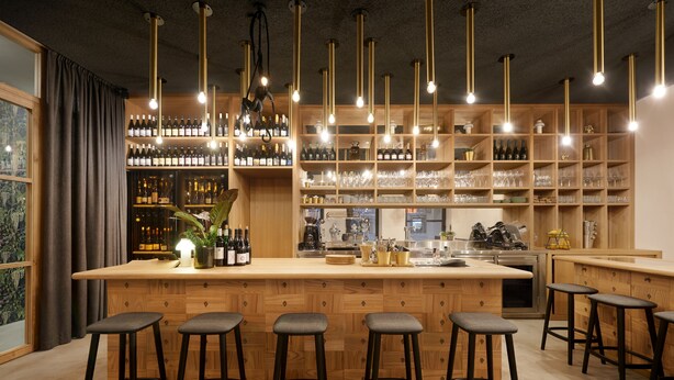 A bar area with wooden shelves stocked with bottles and glasses, a bar counter, and multiple stools. - Goldengel Suite 2, 60sqm, air conditioning, WiFi (Kaltern)