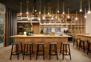 A bar area with wooden shelves stocked with bottles and glasses, a bar counter, and multiple stools.