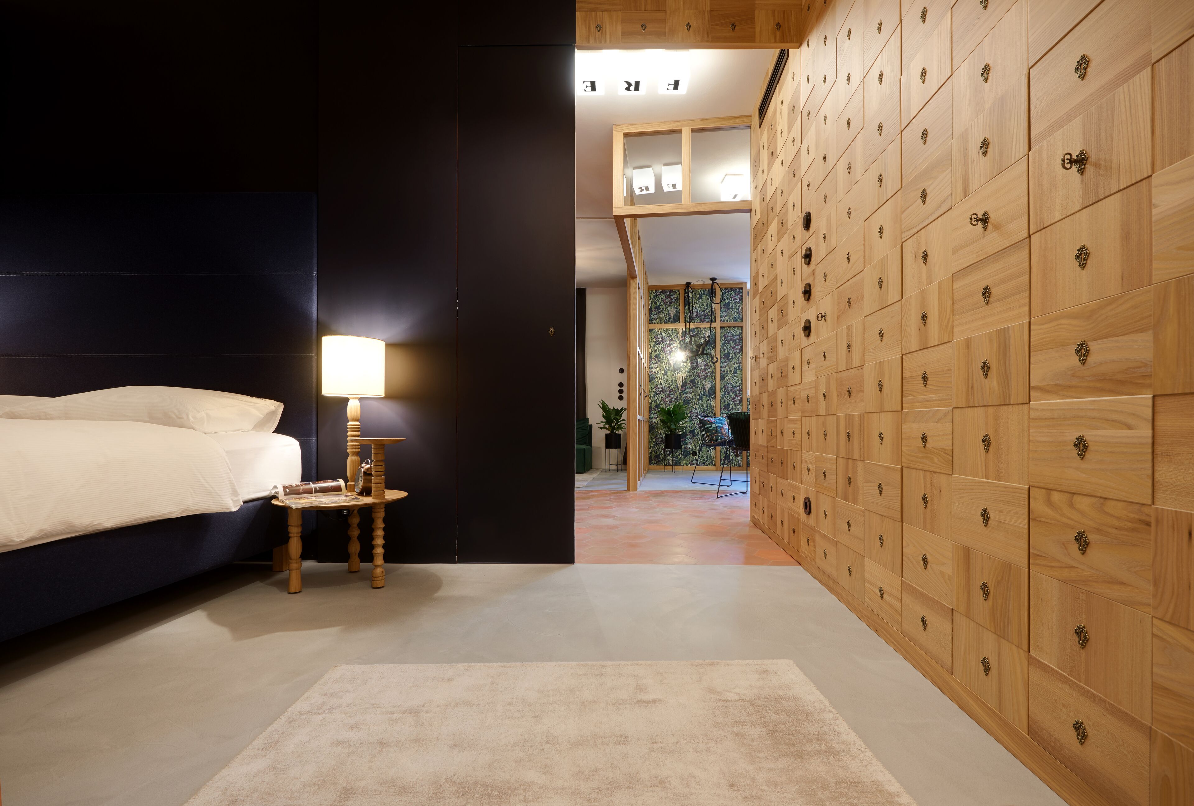 Quarto com cama, mesa de cabeceira, abajur e um guarda-roupa de madeira grande.