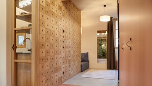 A hallway with a wooden cabinet with multiple drawers, a grey sofa, a window with a view of greenery, and a tiled floor. - Goldengel Suite 2, 60sqm, air conditioning, WiFi (Kaltern)