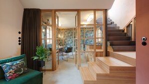 A modern interior with a staircase, a dining area, and a green sofa.