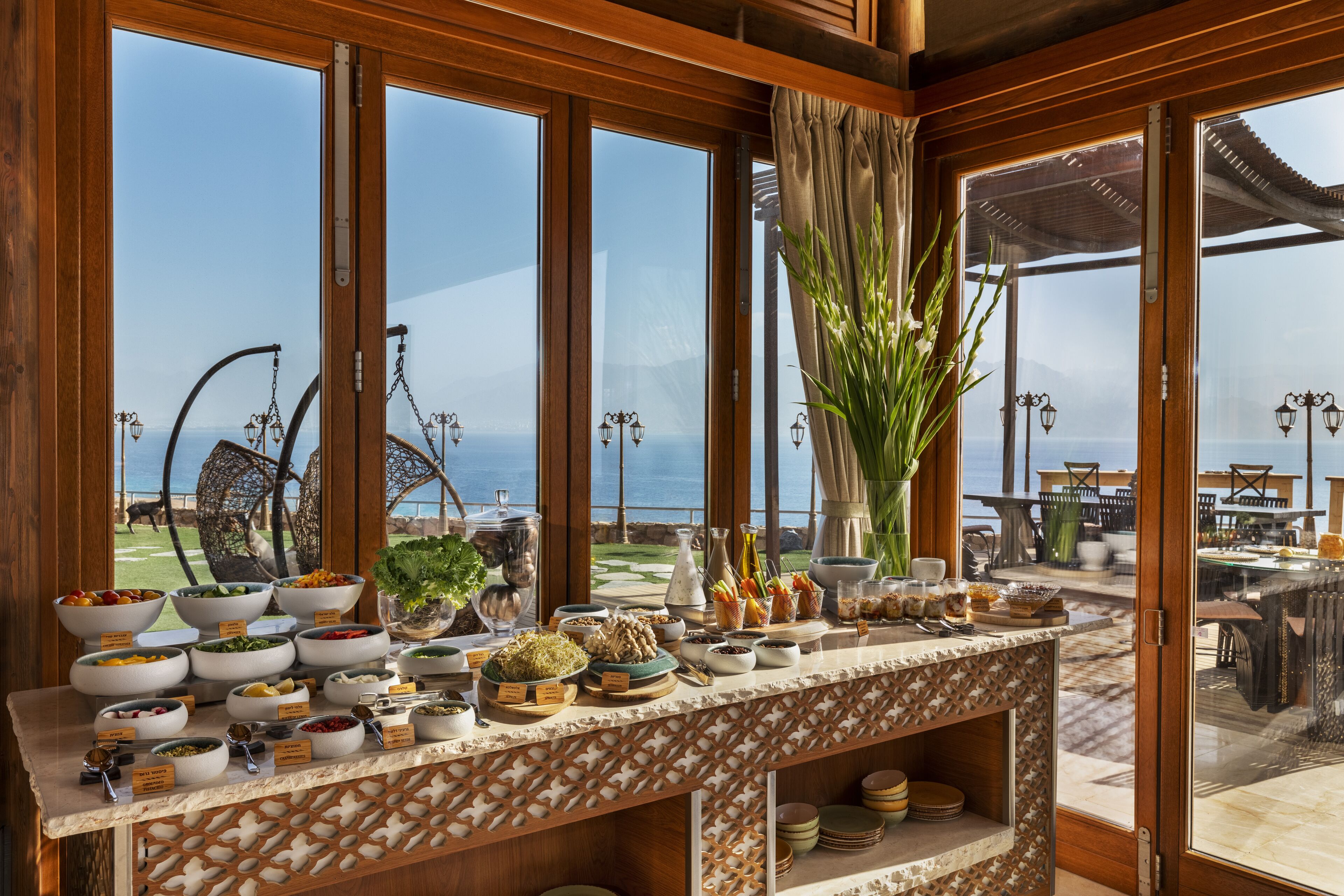 Un buffet proposant une variété de plats, avec une vue sur la mer grâce à de grandes fenêtres.
