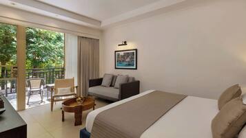 A hotel room with a bed, a sofa, a small table with fruit, and a balcony with chairs.