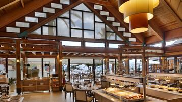 Un restaurante espacioso con techos altos, vigas de madera y amplios ventanales que ofrecen vistas al exterior.
