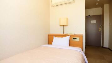 Una habitación de hotel con cama, mesita de noche, lámpara y puerta.