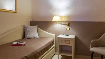 Ein Hotelzimmer mit Bett, Nachttisch, Lampe, Stuhl und einem gerahmten Bild an der Wand.