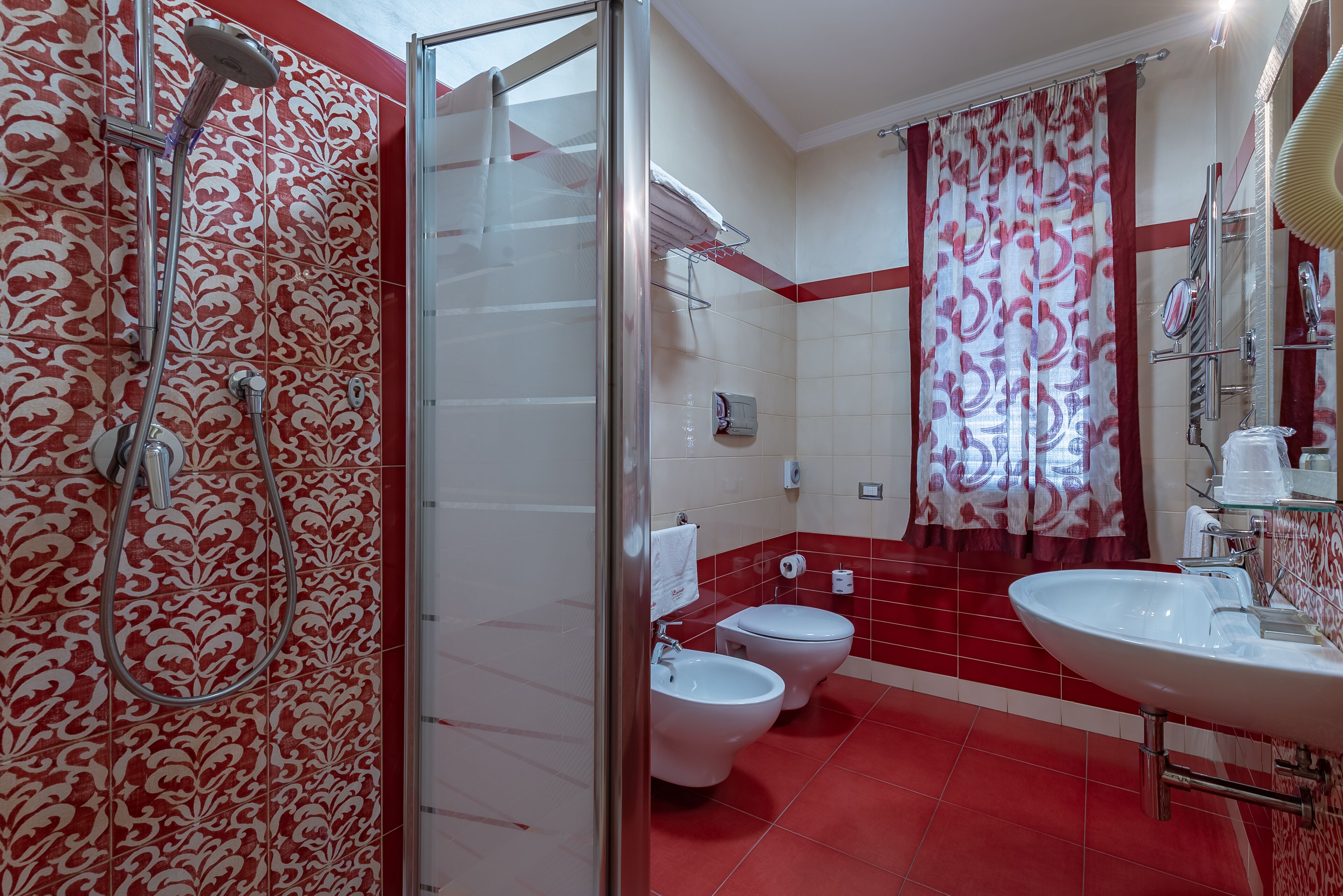 Une salle de bain avec une douche, deux toilettes, un lavabo et une cabine de douche en verre.