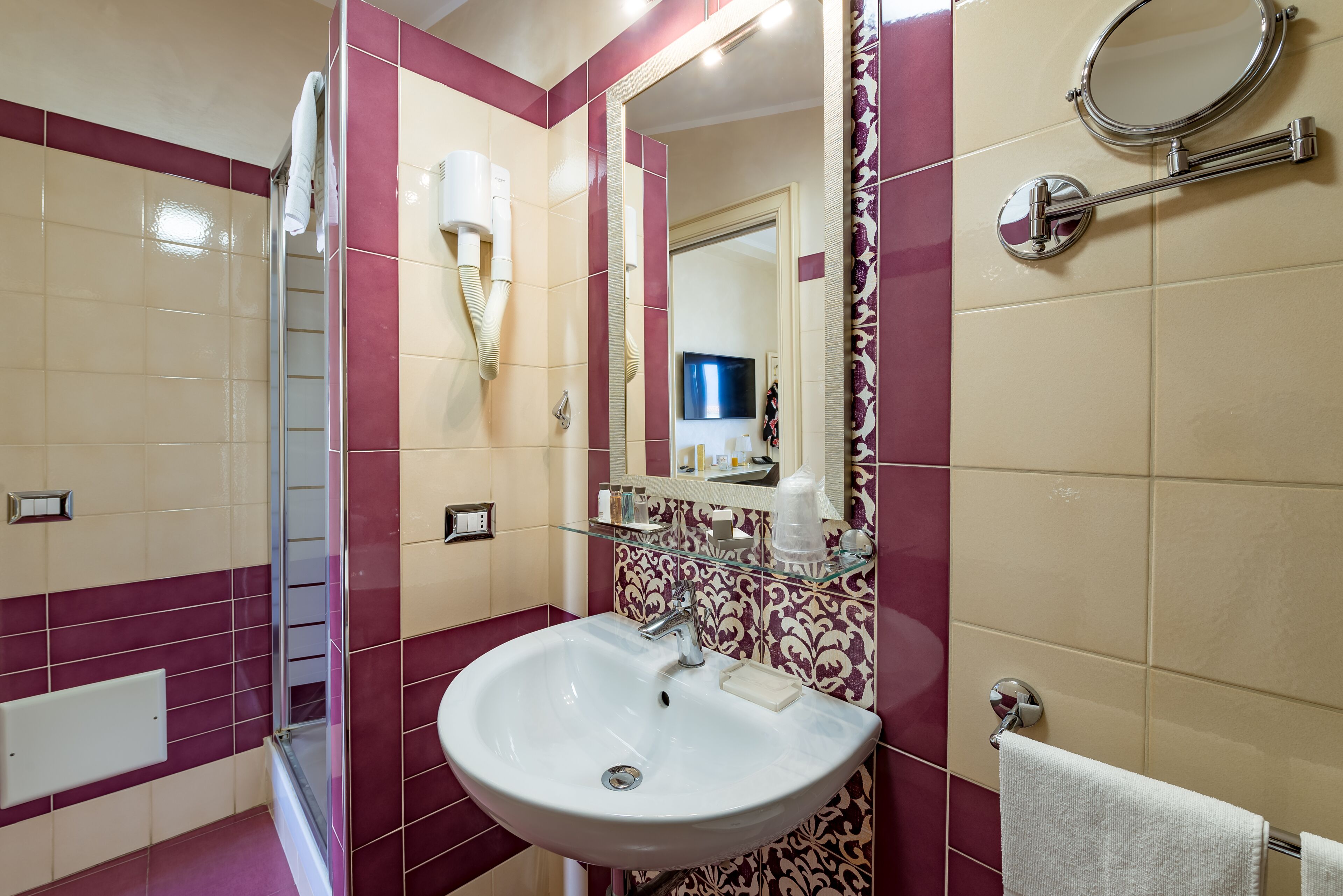 Une salle de bain équipée d’un lavabo, d’un miroir, d’un porte-serviettes et d’une cabine de douche en verre.