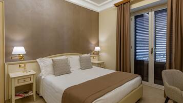 A hotel room with a large bed, two bedside tables with lamps, a chair, and a sliding glass door to the balcony.