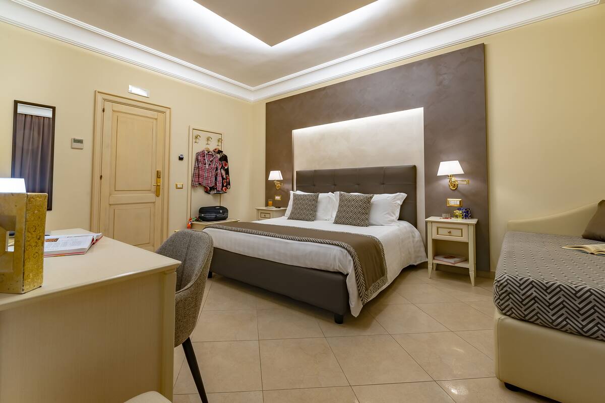 A hotel room with a large bed, bedside tables, a desk, and a chair.