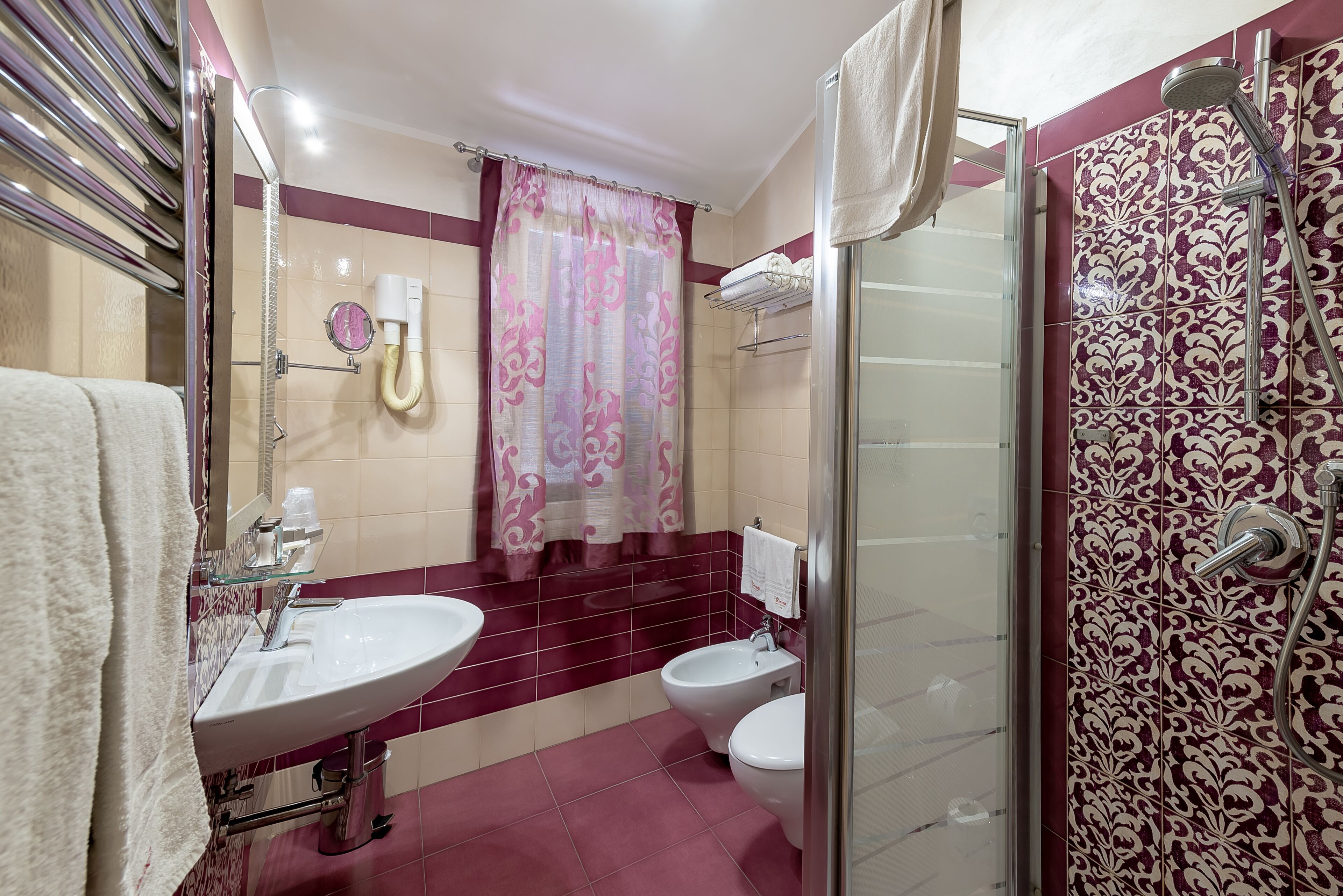 Un baño con cabina de ducha de vidrio, un lavabo y dos inodoros.
