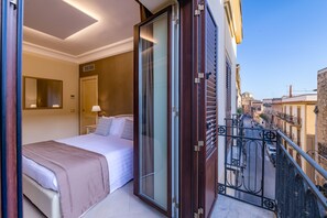 Une chambre d’hôtel avec un lit, un grand miroir, une porte-fenêtre coulissante et un balcon doté d’une balustrade.