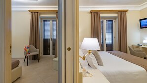 A hotel room with a bed, bedside table, lamp, chair, and a desk with a chair. - Vittorio Emanuele Boutique Hotel (Sciacca)