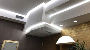 A modern interior with a recessed ceiling, a wooden accent wall, and a framed picture on the left. - Vittorio Emanuele Boutique Hotel (Sciacca)
