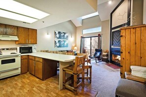 A modern kitchen with wooden cabinets, a central island, and a fireplace.