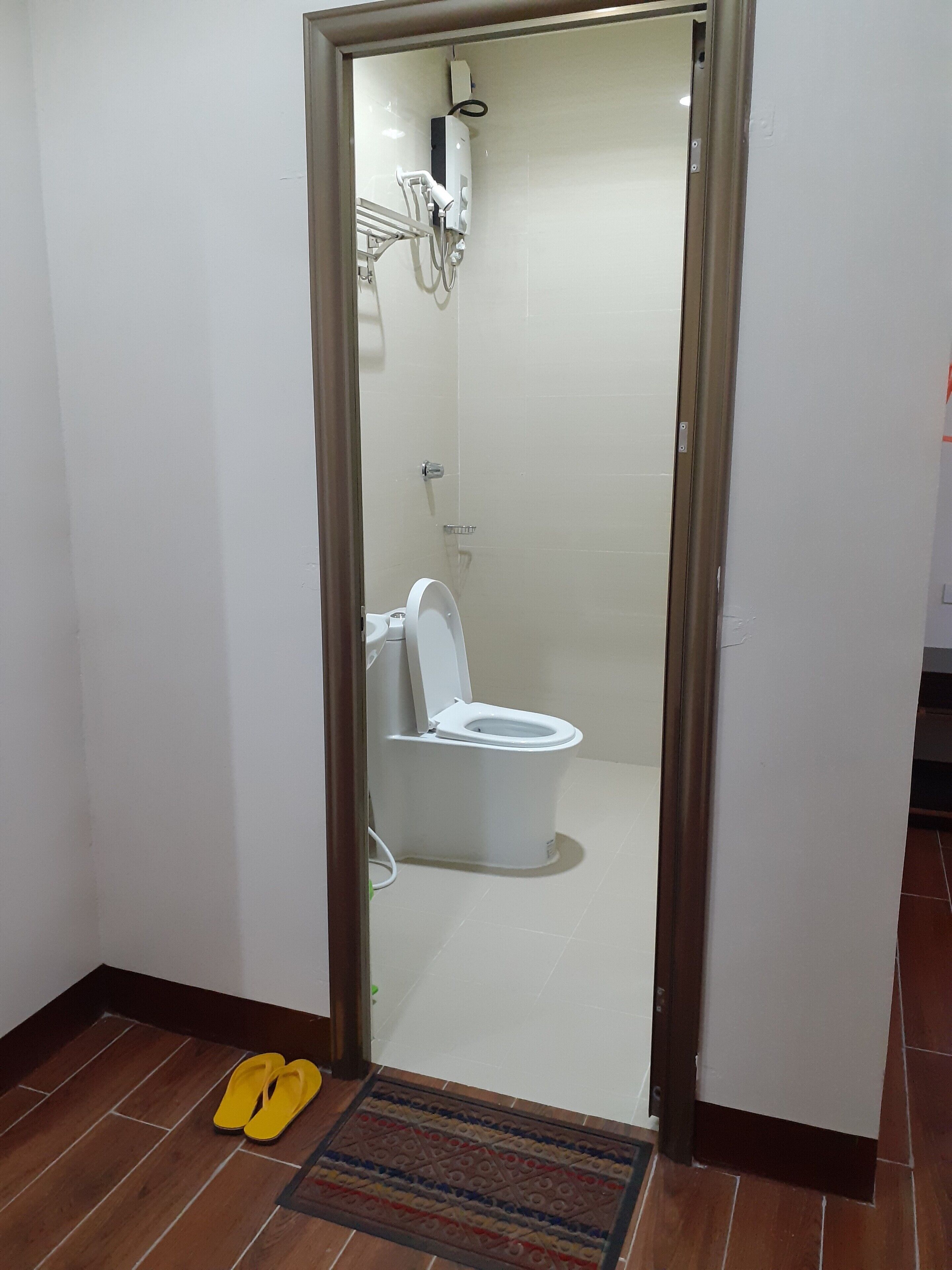 A bathroom with a toilet, a shower, and a towel rack.