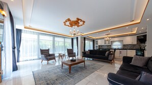 Amplia sala de estar con una gran mesa de centro, asientos cómodos y una cocina equipada con electrodomésticos modernos.