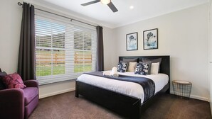 Une chambre à coucher avec un lit, une chaise, une petite table et un ventilateur de plafond.
