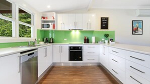 Une cuisine moderne avec des meubles blancs, un pare-feu vert et un lave-vaisselle.