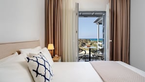 A hotel room with a bed, a nightstand, a lamp, and a view of the sea through an open door. - Cedar Forest Oceanfront Villa, 4BR Private Pool (Naxos)