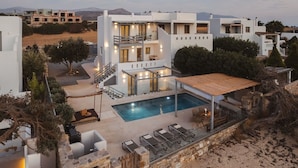 A modern villa with a swimming pool, outdoor seating, and a view of the surrounding landscape. - Cedar Forest Oceanfront Villa, 4BR Private Pool (Naxos)