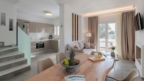A modern kitchen with a dining area, a staircase, and a living room with a sofa and a TV. - Cedar Forest Oceanfront Villa, 4BR Private Pool (Naxos)