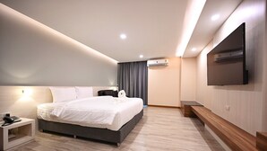 Habitación de hotel moderna con una cama grande, una mesita de noche y un televisor de pantalla plana montado en la pared.