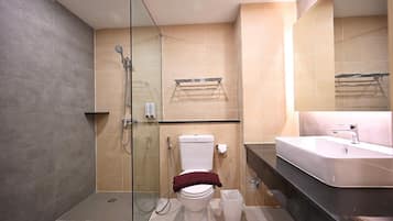 A modern bathroom with a glass-enclosed shower, a white toilet, a sink, and a large mirror.