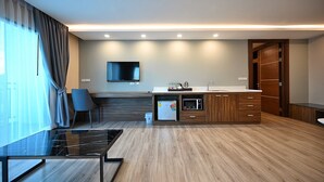 Una cocina moderna con microondas integrado, un lavamanos y un televisor de pantalla plana.