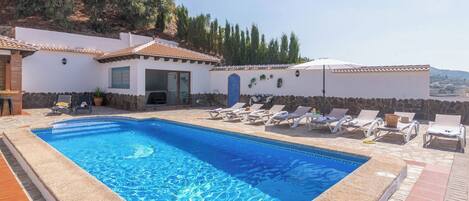 A swimming pool with lounge chairs and a stone wall.