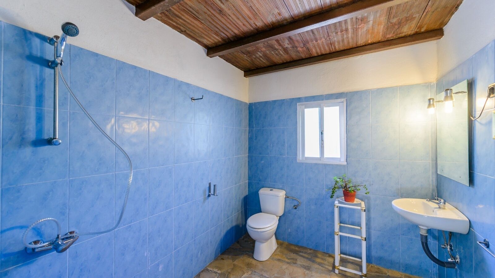 Un baño con azulejos azules, inodoro blanco, lavabo y ducha.