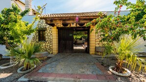 Edifici de pedra amb teulada a dos vessants, entrada amb plantes en testos i un camí empedrat que condueix a la porta.