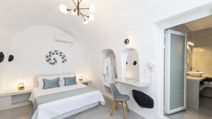 Ein modernes Schlafzimmer mit Bett, Nachttischen, einem Sessel, einem Spiegel und einem durch eine offene Tür einsehbarer Badezimmer.