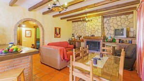 A cozy living room with a fireplace, a television, and a dining area with a glass table. - La Chumbera Órgiva by Ruralidays (Granada)
