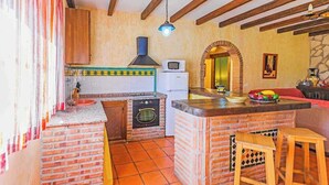 A kitchen with a brick island, a washing machine, and a microwave. - La Chumbera Órgiva by Ruralidays (Granada)