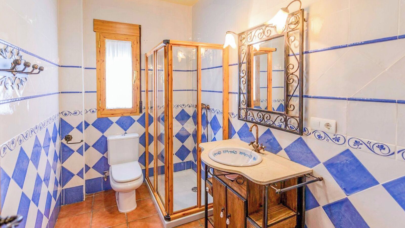 A bathroom with a toilet, shower, and sink, featuring blue and white diamond-patterned tiles.