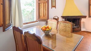 A dining area with a glass table, wooden chairs, and a bowl of fruit.