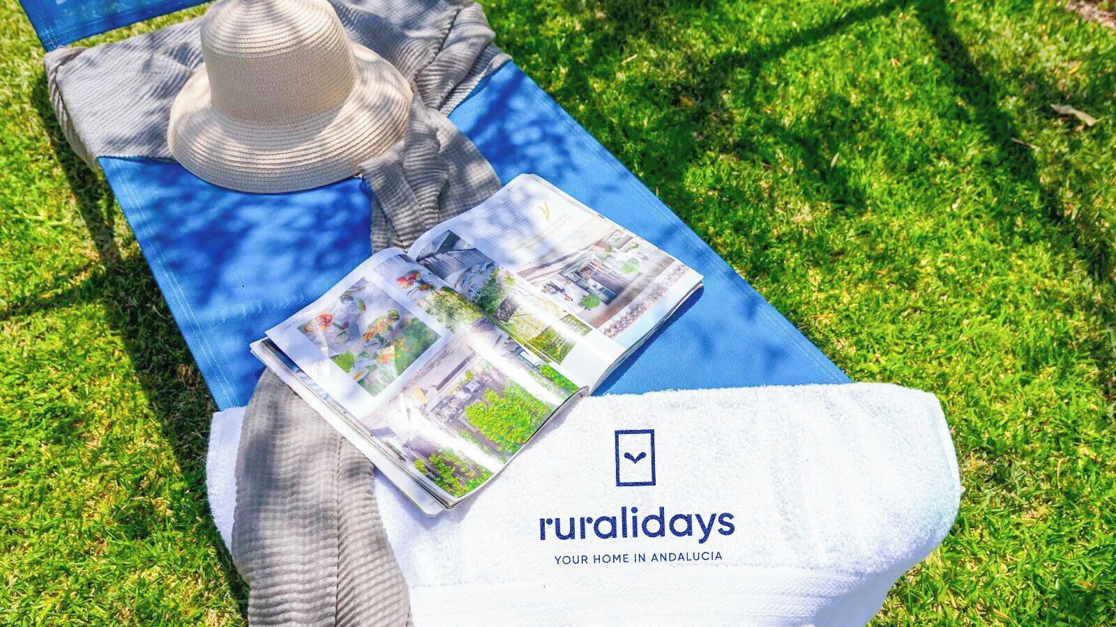 Un fulletó amb el títol 'ruralidays' sobre un estriatge blau, amb un barret i un teixit rayat.