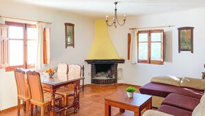 A living room with a fireplace, a dining table with chairs, and a sofa.