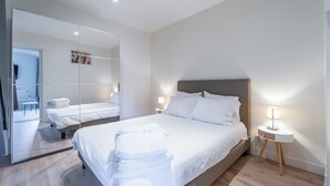 Camera d'albergo moderna con un letto grande, un comodino con una lampada, uno specchio e vista sul bagno.
