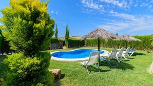 A swimming pool with lounge chairs and a thatched umbrella.