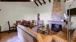 A cozy living room with a stone fireplace, wooden furniture, and a television.