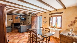 Un comedor acogedor con una mesa de vidrio y sillas de madera, una chimenea y una cocina al fondo.