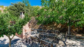 An outdoor seating area with stone walls, a brick structure, and a pergola.