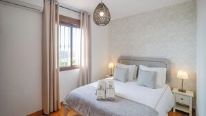 Ein Hotelzimmer mit einem großen Bett, zwei Nachttischen mit Lampen, einem Fenster mit Vorhängen und einer strukturierten Wand.
