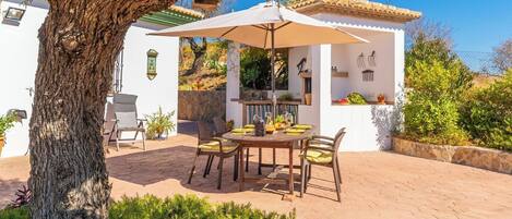 An outdoor patio with a round table, chairs, and a pergola.