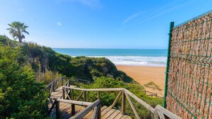 Un escalier en bois menant à une plage d’où l’on a une vue sur l’océan.