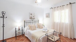 Een slaapkamer met een bed, nachtkastjes, een lamp en gordijnen.